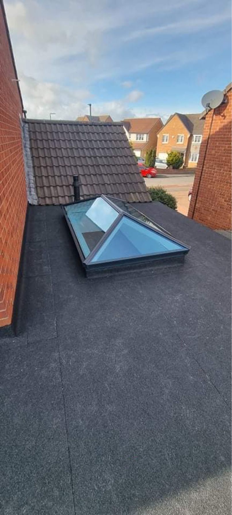 A new flat roof with a glass lantern roof light between two brick walls